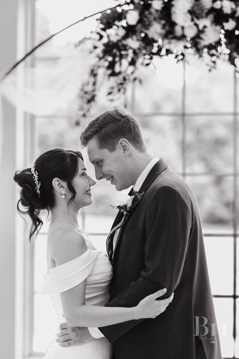 Couple nose to nose under a floral arch